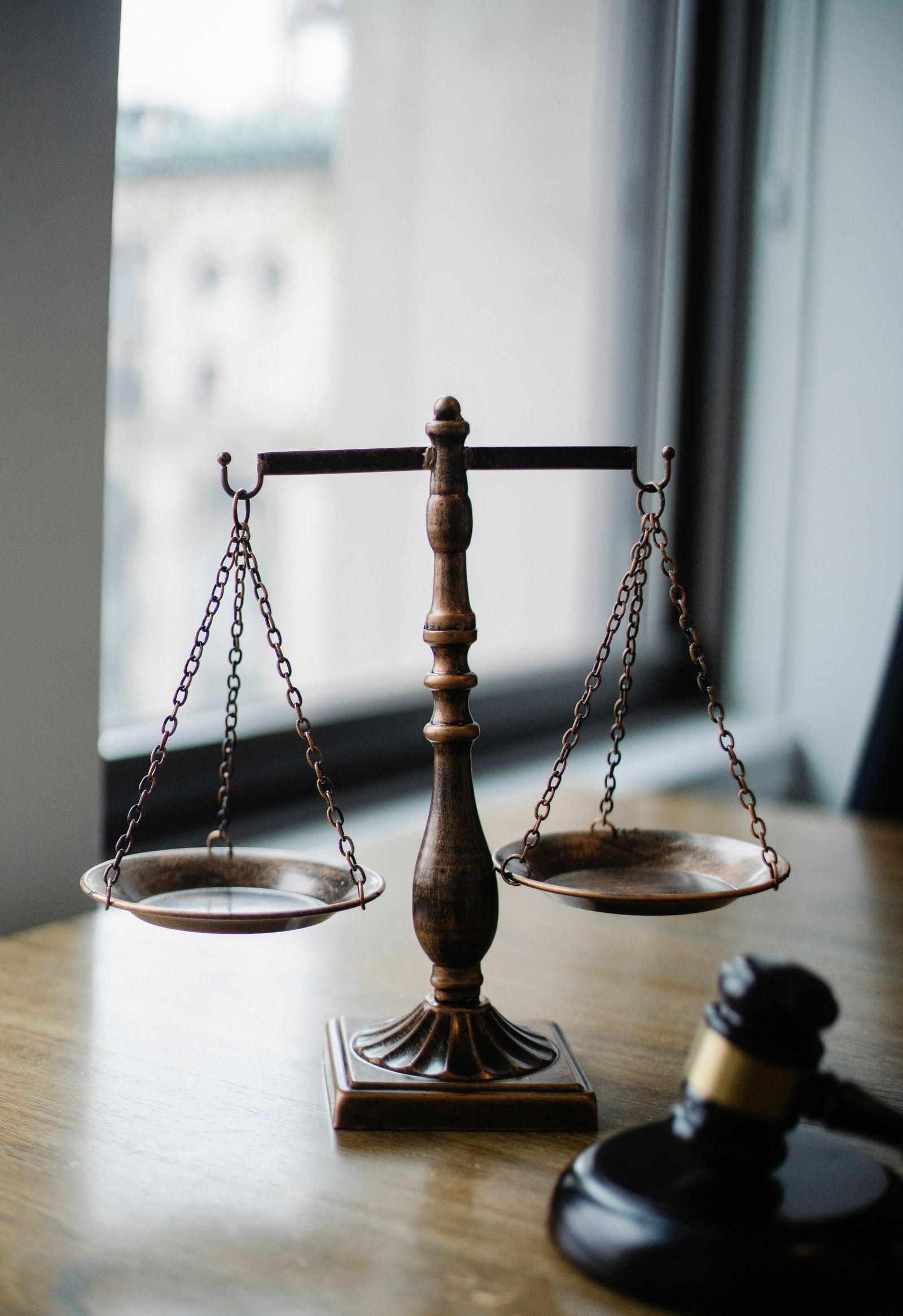 A gavel and scale of justice on a wooden judge's desk
