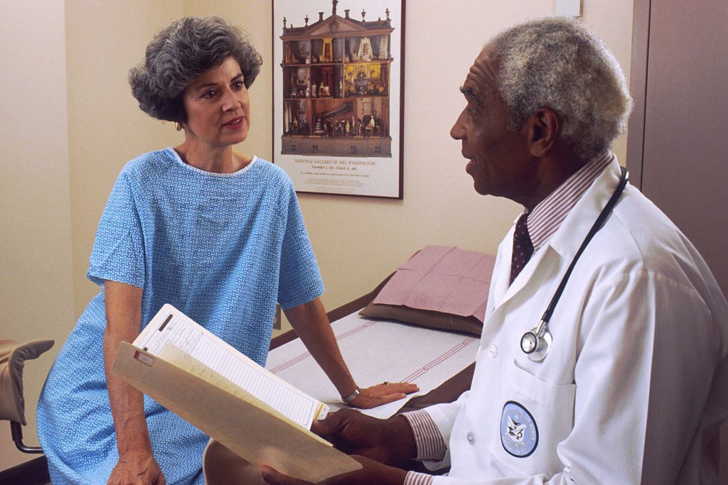 African American male doctor consulting with a patient in an exam room