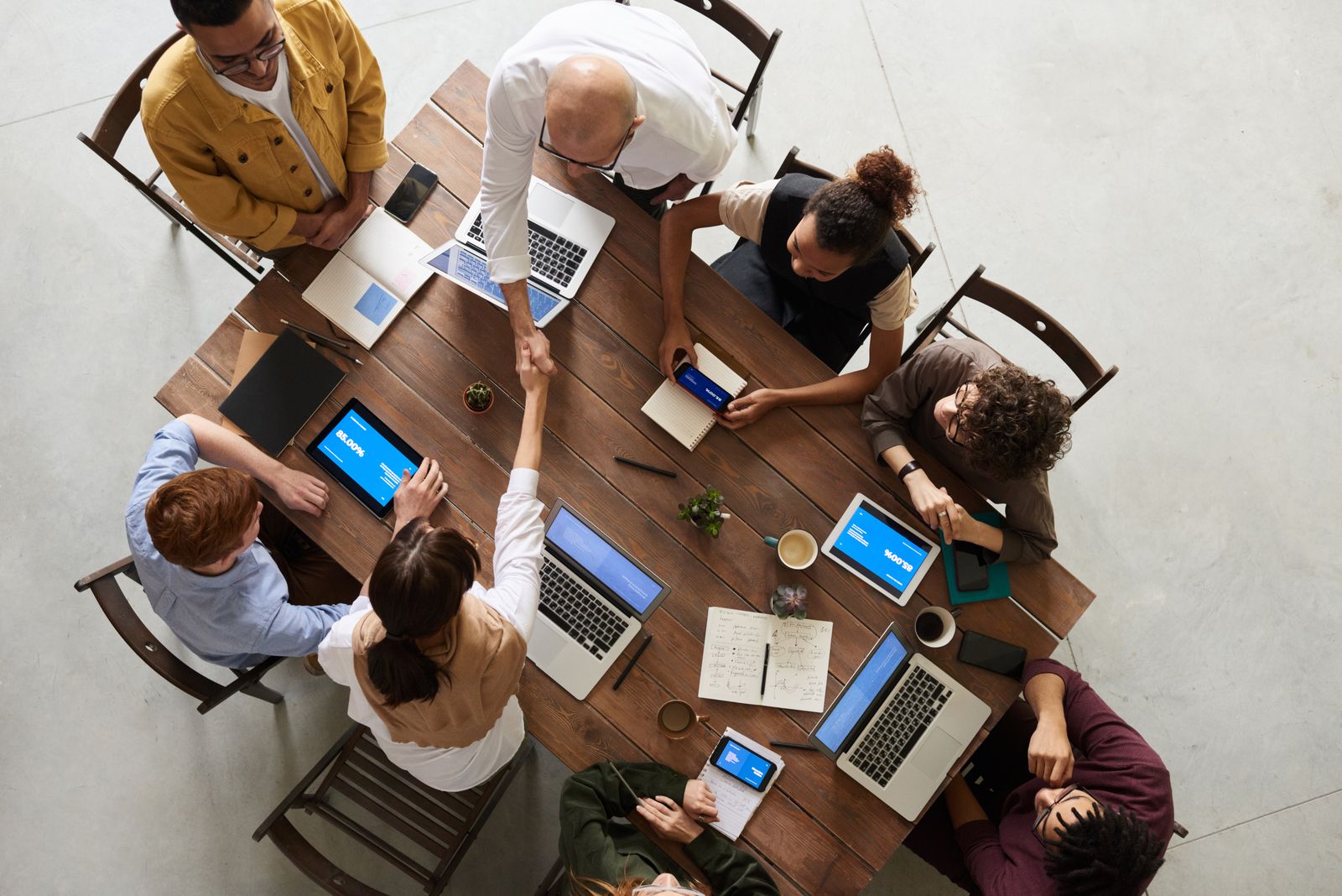 A diverse team collaborating around laptops and tablets in an office setting
