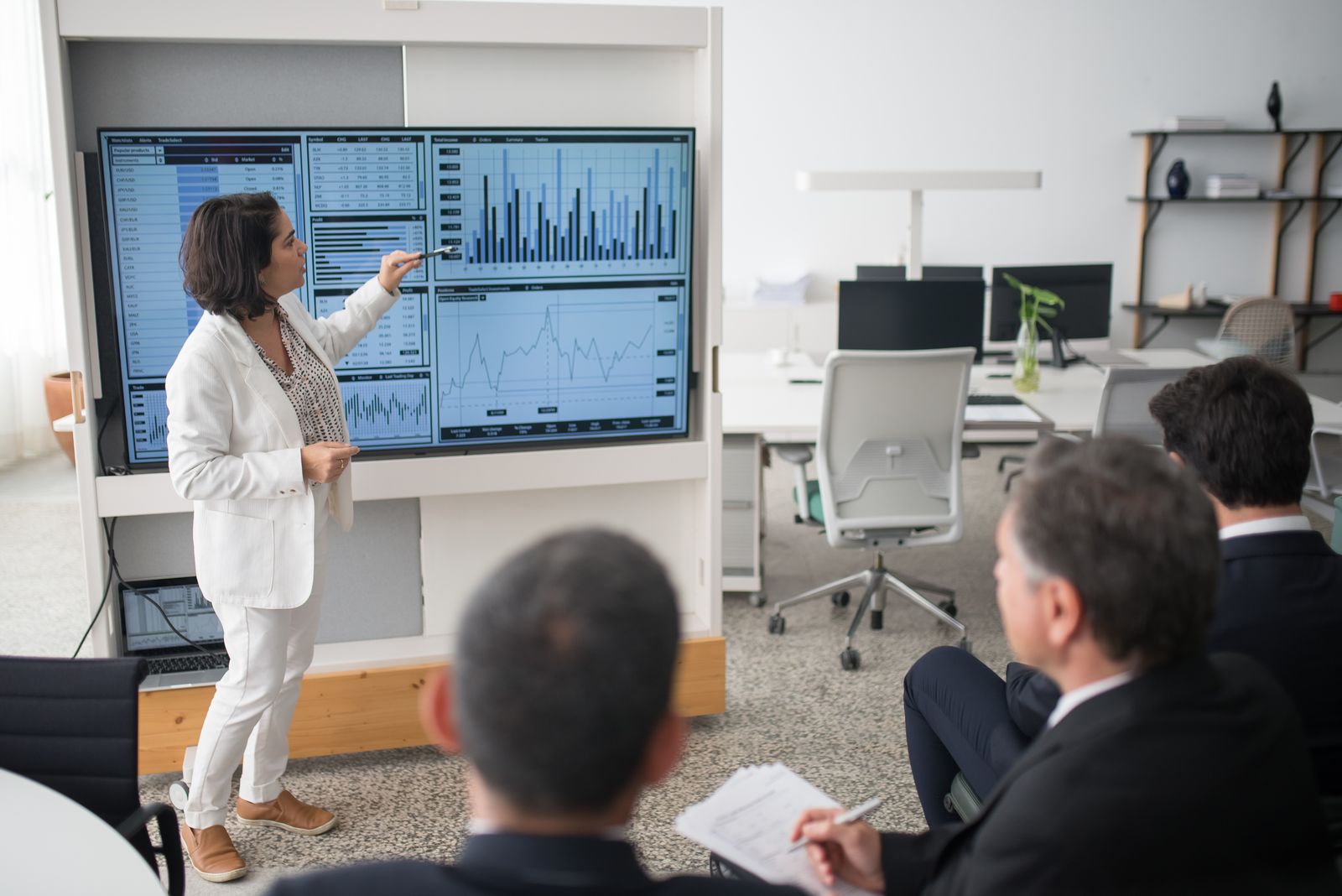 A woman presenting financial data to colleagues in an open office
