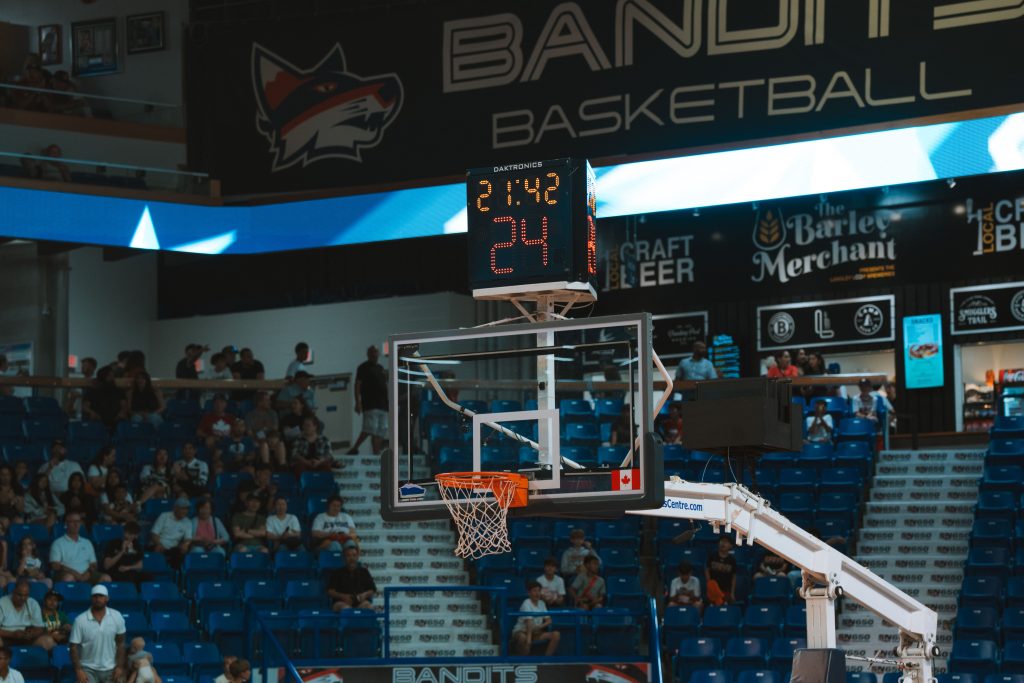A basketball hoop and scoreboard above a filled arena during a game