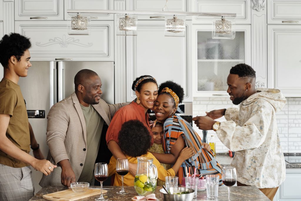 A joyful Black family gathering and embracing together in a kitchen