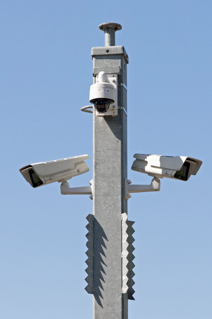 A surveillance camera mounted on a wall, representing facial recognition and wrongful arrests of Black Americans