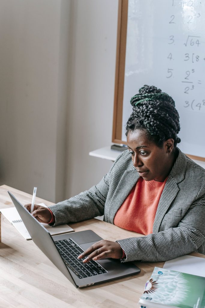 A Black woman learning tech skills on a laptop in a training classroom