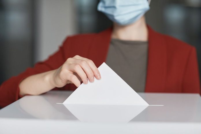 Voter casting ballot in ballot box Person casting a ballot into a ballot box