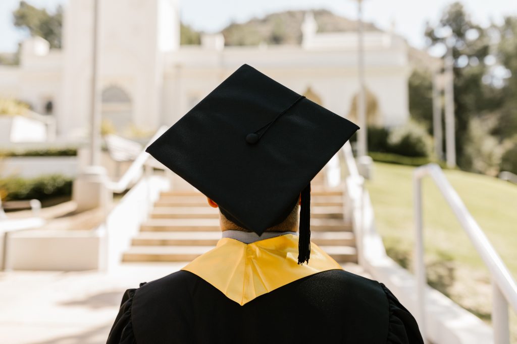 A college graduate in cap and gown standing outdoors.