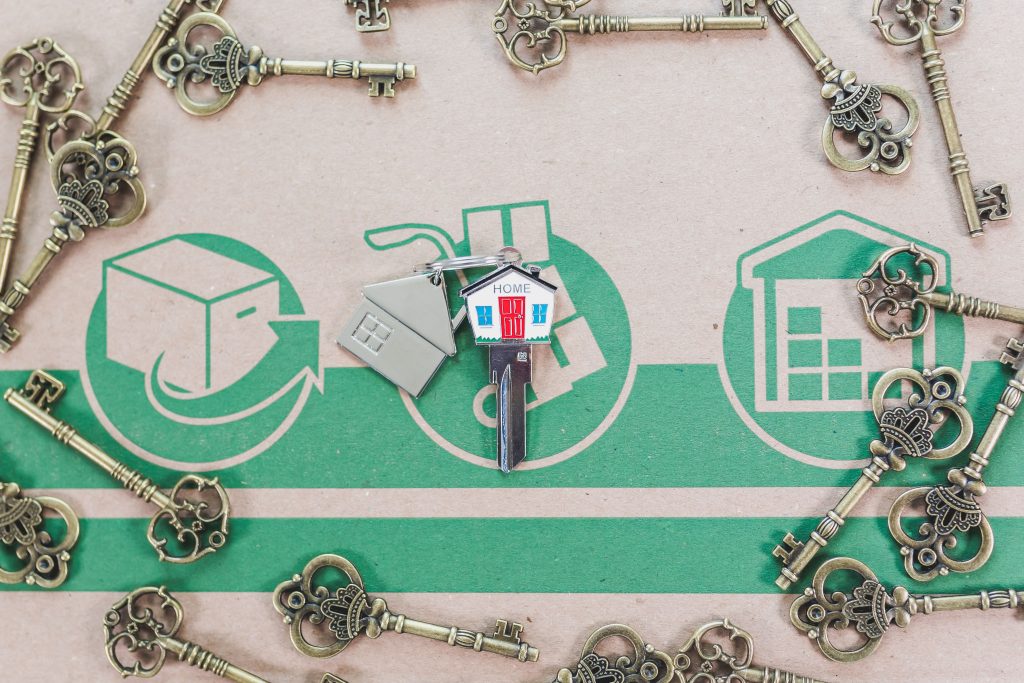 A hand holding house keys in front of a home, representing the Black homeownership and appraisal gap
