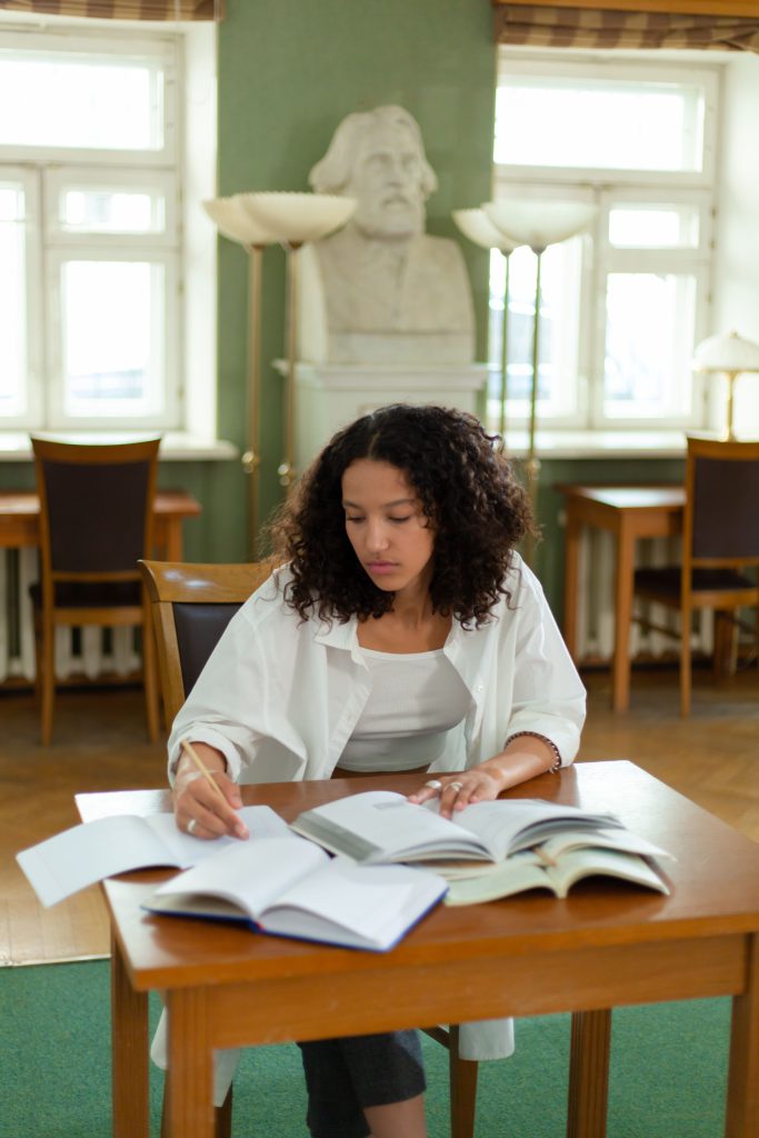 A young student with curly hair writing on paper while completing a scholarship application
