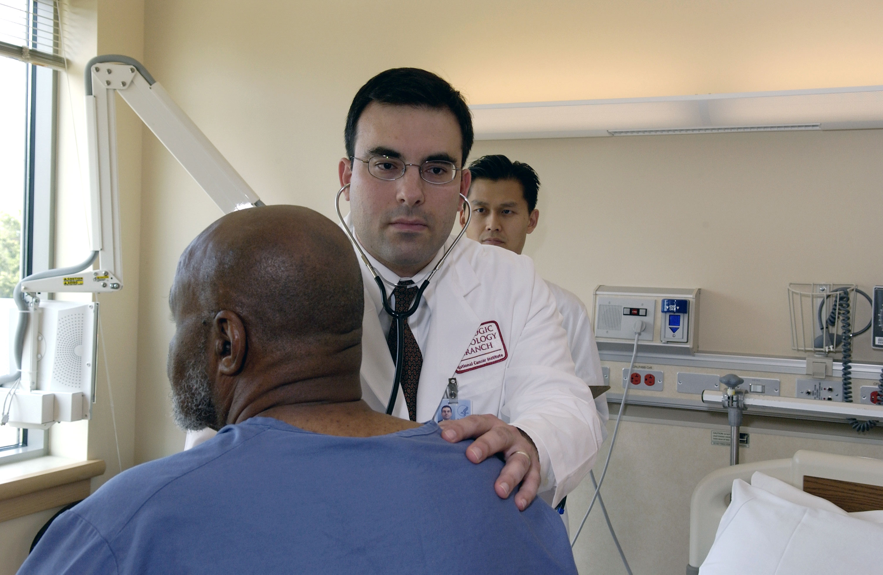 Doctor examining a Black patient in a clinic exam room