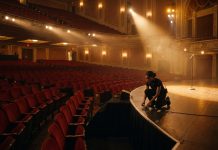 2026 Emmys: Early Black Winners and How to Watch on September 14 Empty awards theater with red velvet seats and a spotlit microphone as a stagehand works