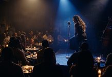 Cassandra Wilson Dies at 70: A Listening Guide to Her Legacy Silhouetted singer with an acoustic guitar performs under blue light in a dim jazz club