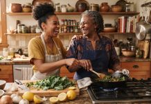 Grandma’s Kitchen Hacks: What Science Backs and What It Doesn’t A Black grandmother and her adult granddaughter laughing while cooking with a cast iron skillet and fresh greens